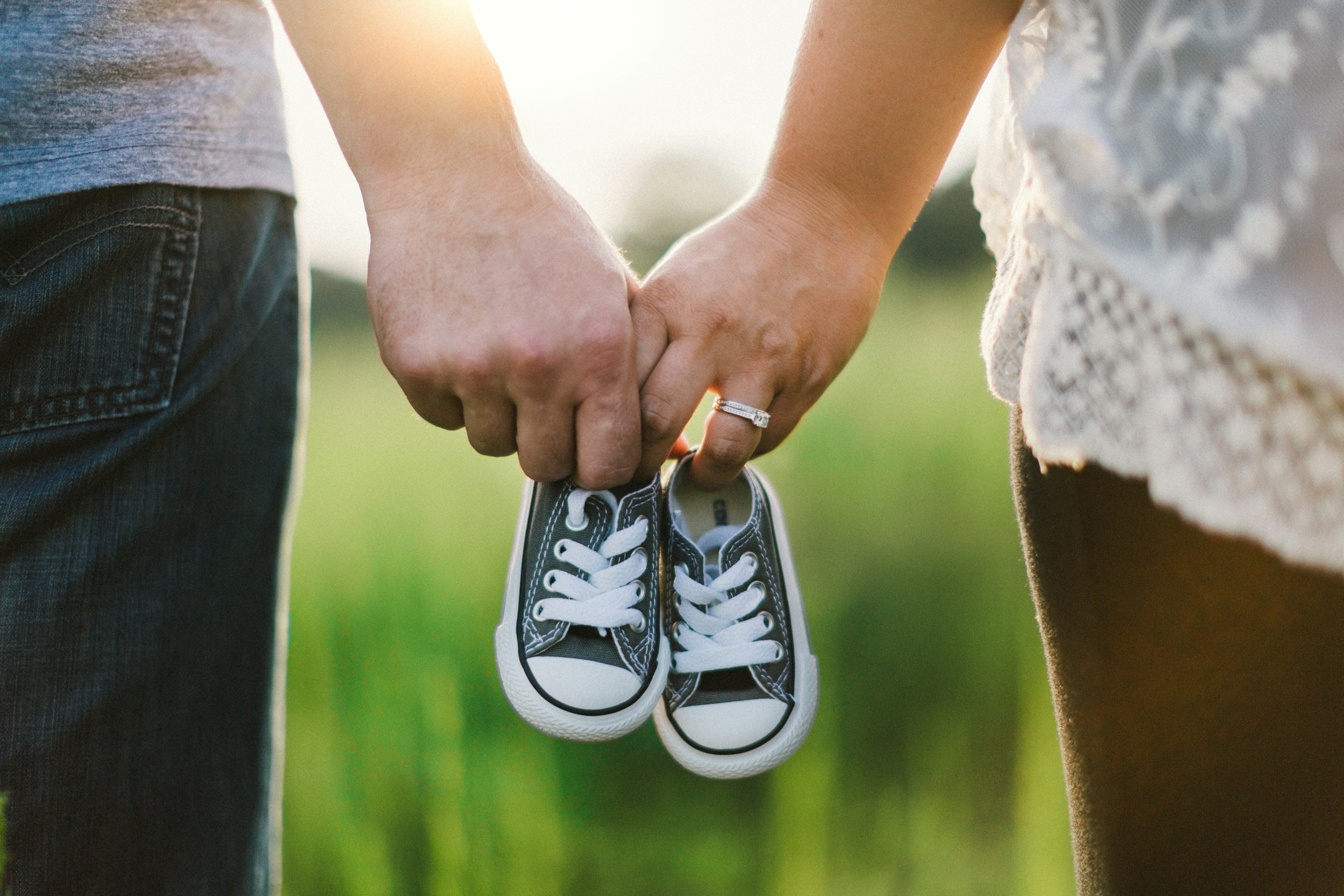 Dos personas sostienen unos zapatos de bebé al aire libre